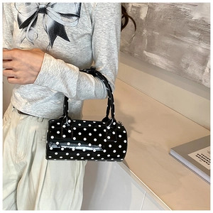 Detailed macro view of a vintage black barrel bag with white polka dots in glossy PU leather