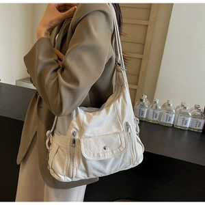 Detail of white PU shoulder bag with pebble texture and multiple silver zipper pockets