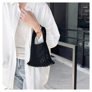 Detail of a black crochet mesh tote bag featuring a hollow honeycomb woven pattern and handle