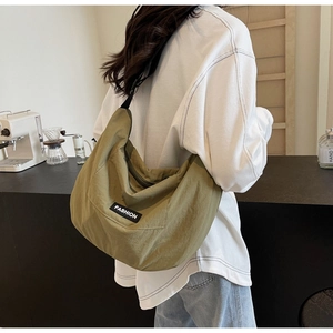 Deep olive green canvas hobo bag worn by a model in a modern cafe setting