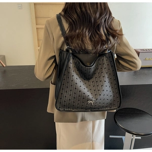 Back view of a dark grey backpack with bow pattern and silver metallic bow detail