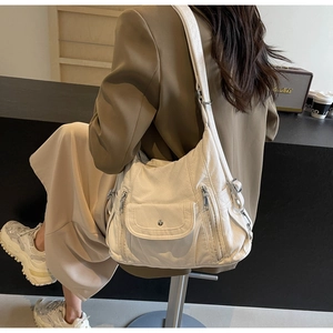 Detail view of cream PU leather crossbody bag with multi-pocket design and wide strap