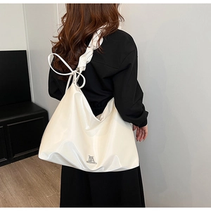 Detailed view of cream PU leather tote bag featuring a pleated shoulder strap and bow