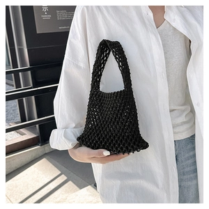 Close-up of minimalist black hand-woven tote bag with intricate hollow mesh pattern