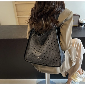 Detailed macro view of gray fabric tote with black bow jacquard and leather handles