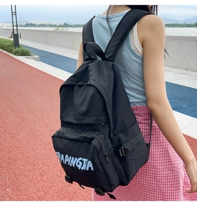 Detail of a black nylon backpack featuring a front zipper pocket with blue logo printing