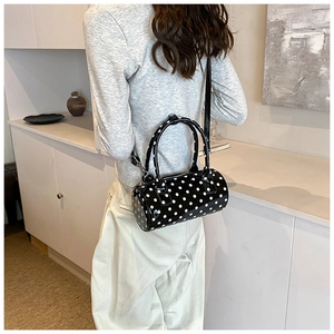 Chic cylindrical black and white polka dot PU leather crossbody bag worn by model