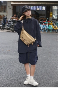 Detailed shot of khaki nylon waist bag with three front pockets on navy windbreaker jacket