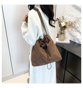 Brown corduroy tote bag with red heart pattern shown on model in a cozy indoor setting