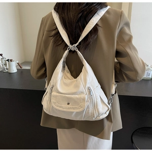 White textured PU leather backpack with multiple zipper pockets shown on a model