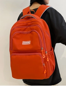 Detail view of orange nylon backpack featuring breathable mesh straps and side pockets