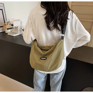 Detail of army green nylon crescent bag with adjustable black strap and FASHION label