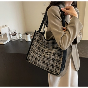Close-up of a large capacity plaid tote bag with bow detail worn by a model