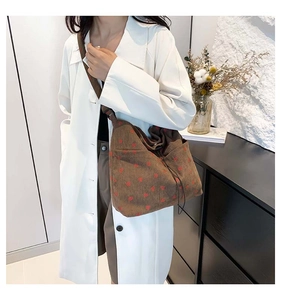 Close-up of brown corduroy crossbody bag with red strawberry pattern and texture