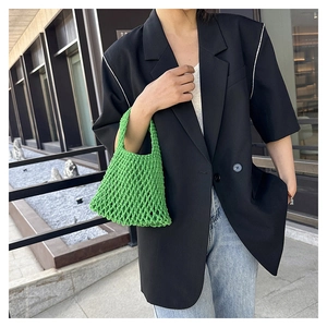 Detail view of vibrant green woven cotton handbag featuring hollow mesh texture in daylight
