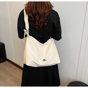 Detail of off-white PU leather crossbody bag with drawstring knot and black logo branding