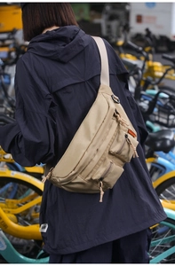 Detail of khaki nylon waist bag with multi-pocket design and adjustable strap