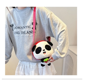 Detail shot of plush panda crossbody bag with red strawberry accent and red strap