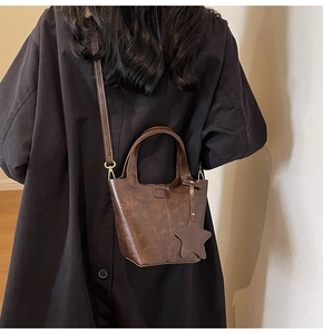 Détail du sac seau marron foncé avec coutures verticales et accessoire breloque étoile