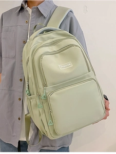 Detail view of green nylon backpack showing side compartments and mesh shoulder straps