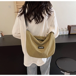 Detail of mustard green canvas crossbody bag featuring a black FASHION label and strap