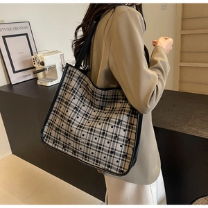 Detail of the woven checkered tote bag featuring a silver bow charm and black leather trim