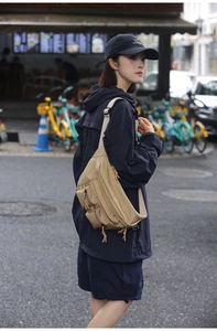 Detail view of khaki nylon fanny pack with multi-pocket design on casual street model