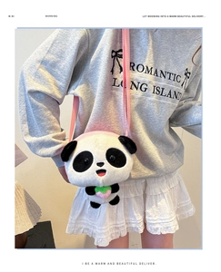 Detail view of plush panda crossbody bag with pink strawberry decor on grey hoodie outfit