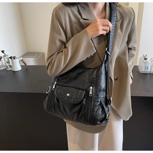 Detail of black textured PU leather shoulder bag with functional dual zipper pockets