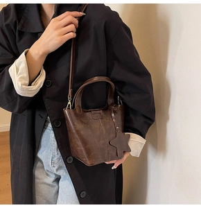 Détail d'un sac seau vintage en cuir PU marron foncé avec pendentif étoile porté