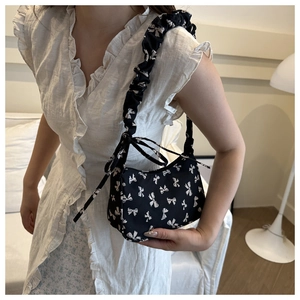 Close-up of black floral nylon handbag with white bow prints and ruched shoulder strap