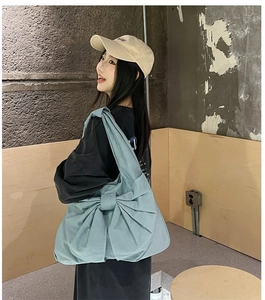Détail du sac cabas en denim bleu clair avec grand nœud porté par un mannequin