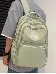 Detail showing the multi-pocket zipper design and mint green nylon fabric of the backpack