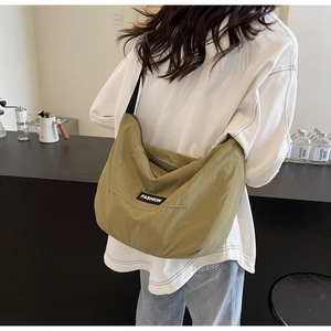 Detail view of military green fabric crossbody bag with FASHION label in a cafe