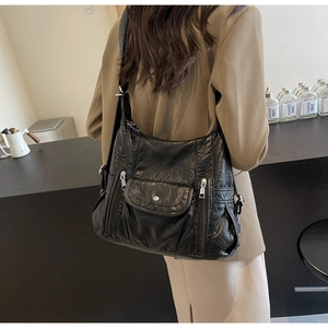 Detail of black textured PU leather hobo bag with functional side zippers and pockets