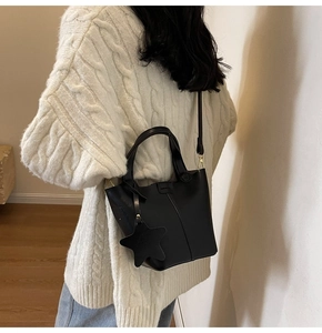 Mannequin portant un sac seau en cuir noir mat avec breloque étoile et poignée