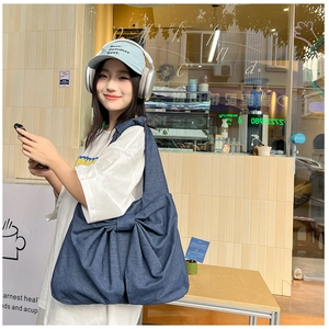 Détail du grand sac cabas en denim avec un nœud décoratif en finition bleu délavé classique