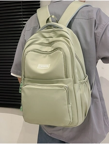 Detail view of sage green nylon backpack featuring multiple pockets and fashion label