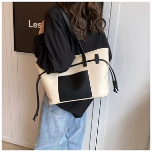 Detailansicht der cremefarbenen Canvas-Tasche mit schwarzem Besatz und Kordelzug am Modell