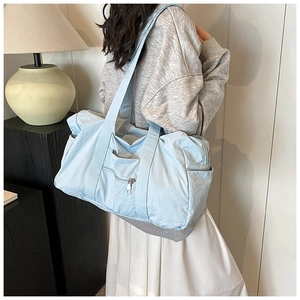 Macro detail of a light blue nylon shoulder bag showing spacious side view and wide straps