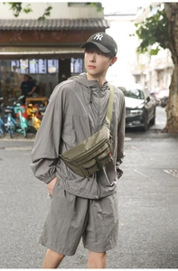 Olive green nylon fanny pack with utility pockets shown in a street style outfit