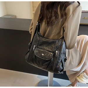 Detail of black pebbled PU leather hobo bag with silver zippers shown on a model