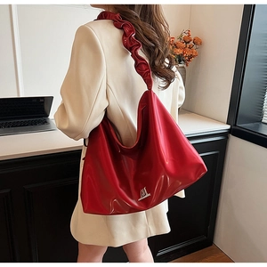Detail of red large capacity shoulder bag with ruched strap and glossy PU leather texture