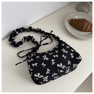 Black canvas shoulder bag with white bow pattern and stylish ruched handle design