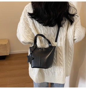 Détail d'un sac seau en similicuir noir avec pendentif étoile et ferrures dorées