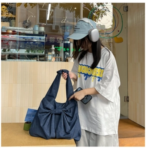 Détail du grand sac cabas en jean bleu foncé avec un nœud décoratif et anse nouée