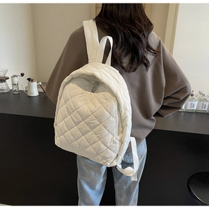 Nahaufnahme des weißen gesteppten Rucksacks mit Karomuster und Silberreißverschluss