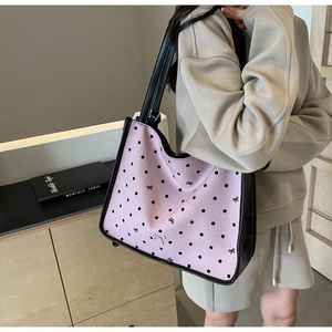 Detail of light pink tote bag with black polka dots and butterfly patterns on model