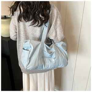 Light blue nylon travel tote bag shown from back view on a model for a casual look