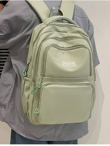 Detail of light green nylon backpack with multiple zippers and FASHION logo label